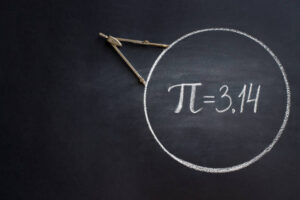 The Greek letter Pi, the ratio of the circumference of a circle to its diameter, is drawn in chalk on a black chalkboard with a compass in honor of the international number Pi for March 14